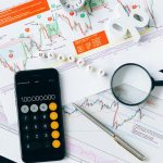 Flat lay of charts, calculator, and magnifying glass on office desk for market analysis.